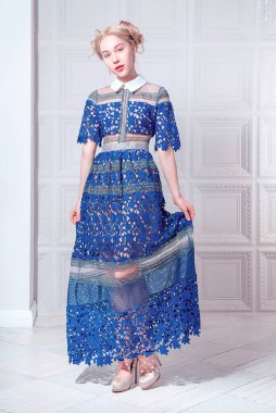 Lacivert elbiseli, elinde kuş kafesi olan hoş bir genç kadın.