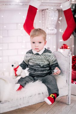 Genç bir çocuğun Noel portresi şöminenin ve Noel ağacının etrafında rahat bir atmosfer.