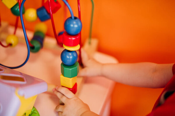 Happy laughing boy 1-2 years old having fun in ball pit on birthday party in kids amusement park and indoor play center. Child playing with colorful balls in playground ball pool. Activity toys for little kid.