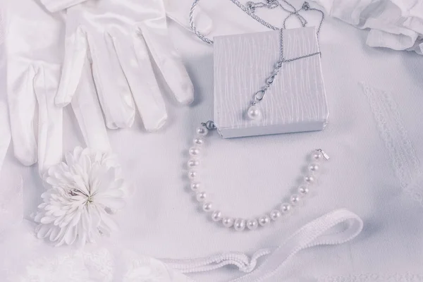 White bridal accessories for wedding background with pearls, white satin ribbons and lace, gloves, bracelet,flat lay for fashion blog, top view