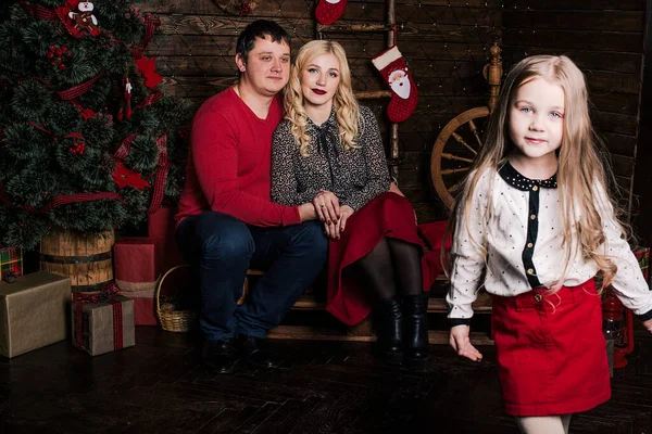 美しい赤の若い家族が一緒にクリスマス休暇を楽しんで 素敵な装飾されたクリスマスツリーの横にあるリビングルームの床に座って — ストック写真