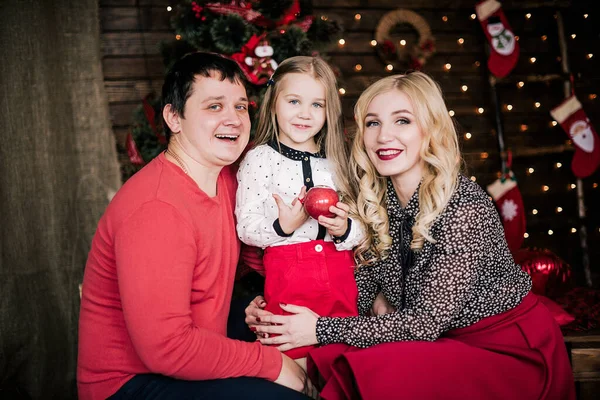 年轻貌美的红衣家庭共度圣诞佳节 坐在装饰精美的圣诞树旁的客厅地板上 面带微笑 — 图库照片