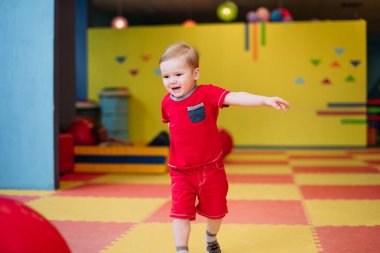 Gülen çocuk 1-2 yaşında, çocuk parkında ve oyun merkezinde doğum günü partisinde top havuzunda eğleniyor. Çocuk oyun parkında renkli toplarla oynuyor. Küçük çocuk için oyuncaklar.