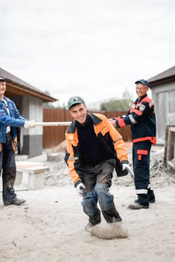 İş, inşaat, takım çalışması ve insanların konsepti - açık havada gülen inşaatçılar grubu