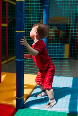 Gülen çocuk 1-2 yaşında, çocuk parkında ve oyun merkezinde doğum günü partisinde top havuzunda eğleniyor. Çocuk oyun parkında renkli toplarla oynuyor. Küçük çocuk için oyuncaklar.