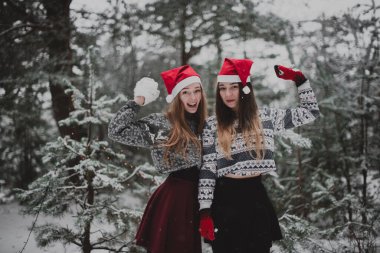 İki genç yeniyetme kız arkadaş bir arada. İki kız kardeşin moda portresini yakın çekin. Kışları eğlenin, süveter giyin, en iyi arkadaşlar açık havada, karlı havada.