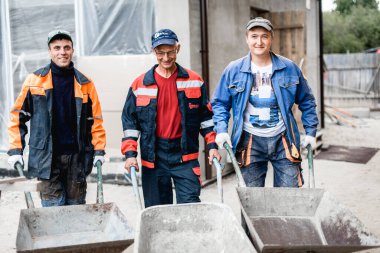 İş, inşaat, takım çalışması ve insanların konsepti - açık havada gülen inşaatçılar grubu