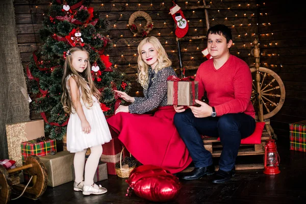 年轻貌美的红衣家庭共度圣诞佳节 坐在装饰精美的圣诞树旁的客厅地板上 面带微笑 — 图库照片