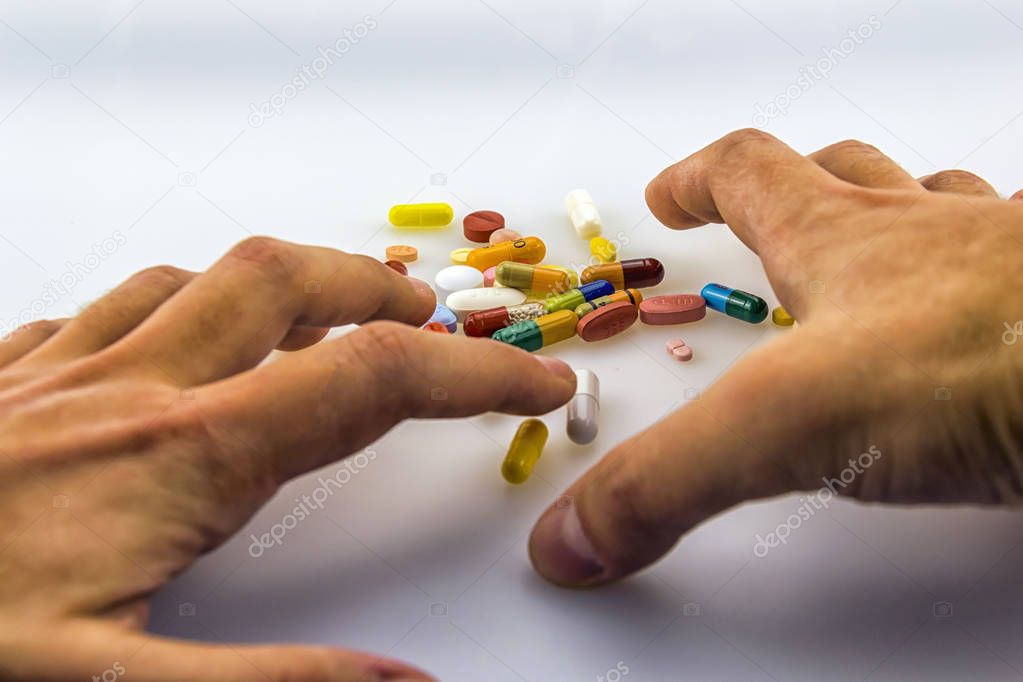 Male hand trying to grab medication isolated on white background suggesting the idea of medication or painkiller addiction.