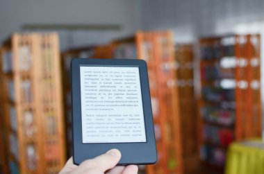Geleneksel kitaplar ile klasik kütüphanede Ebook okuyucu. Teknolojik ilerleme kavramı. 