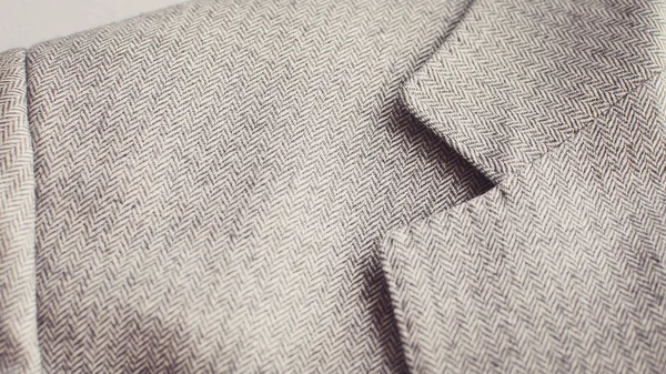 Close up of light grey tweed woolen tweed coat or jacket with a collar fragment.