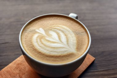 Tahta masadaki kahve fincanını kapat, üstünde kalp izi var. Seçici odak.