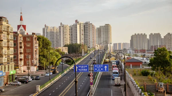 Gün batımında yoğun trafikte ilerleyen arabalı Harbin caddeleri.
