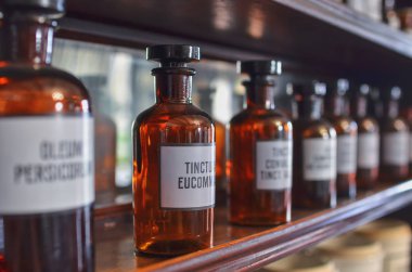 Eczane müzesinin içi. Cam şişelerin üzerinde Latince yazılar olan beyaz etiketler var. Simyacı şişeleri konsepti.