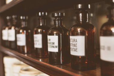 Eczane müzesinin içi. Cam şişelerin üzerinde Latince yazılar olan beyaz etiketler var. Simyacı şişeleri konsepti.