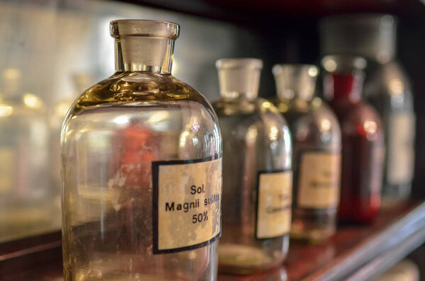 Interior of drugstore museum. Glass bottles have white labels with Latin inscriptions on them. Alchemist bottles concept.