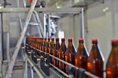 Glass bottles in row on the conveyor belt. Selective focus.