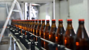 Glass bottles in row on the conveyor belt. Selective focus.