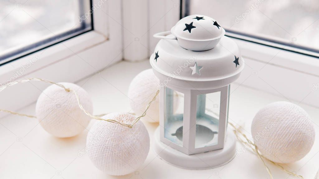 White candleholder and cotton light ball garland on the window sill.