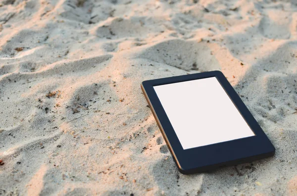 E-book reader on the sand. Place for text.
