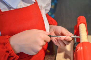 Boy is learning woodworking with a wood-crafting machine tool. Turning wood on a lathe. Selective focus.