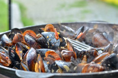 Fresh mussels roasted on a grill pan. Seafood cooked outdoors. Selective focus