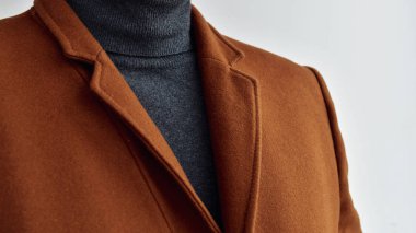 Close up of mens fashionable brown woolen coat combined with grey sweater. Selective focus.