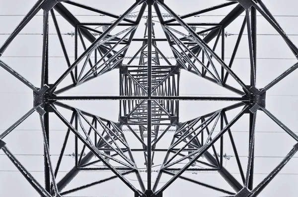 Frozen electrical tower from inside view. Industrial geometry of lines.