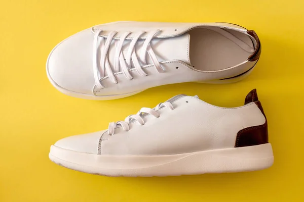 一双黄色背景的白色运动鞋 — 图库照片
