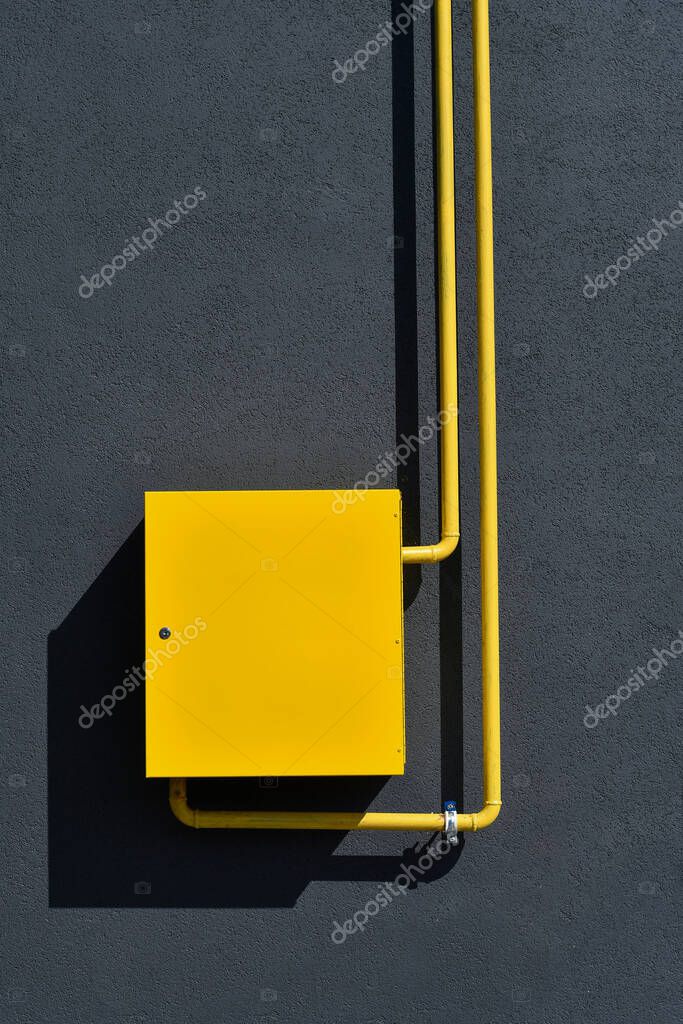 Caja de contadores de gas amarillo con tuberías sobre fondo gris grunge
