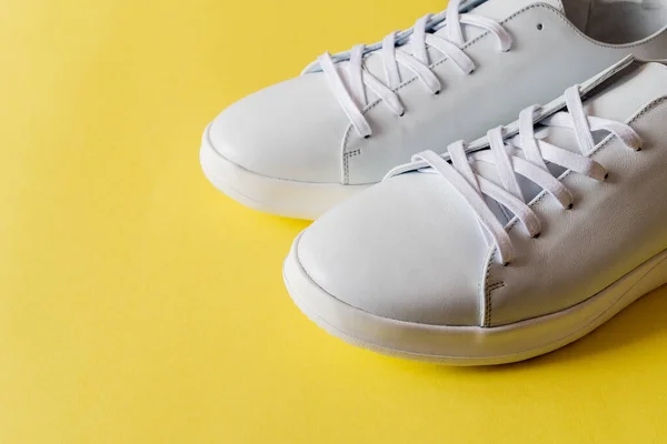 Een Paar Witte Leren Sneakers Een Levendige Gele Achtergrond Kopieerruimte — Stockfoto
