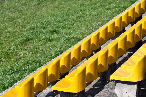 体育场上的黄色塑料座位和绿草 — 图库照片