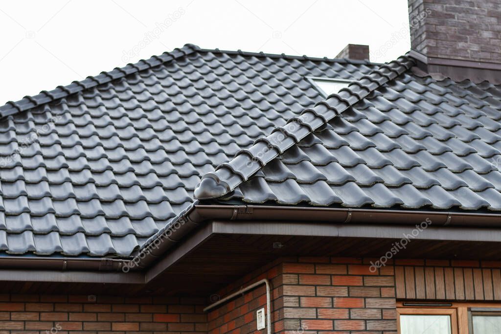 Brown ceramic tile roof.  Modern roofing materials. Roof of the house on the background of transparent sky.