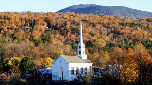 Egy fehér új angliai templom egy domboldalon borított őszi lombozat Stowe Vermont — Stock Fotó