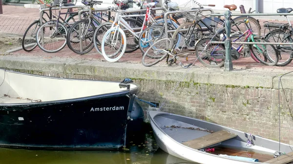 AMSTERDAM, NEDERLÄNDERNA OKTOBER, 12, 2017: många cyklar och bågen på en båt vid en kanal i amsterdam — Stockfoto