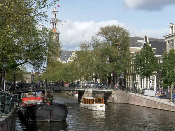 AMSTERDAM, PAÍSES BAJOS 12 DE OCTUBRE DE 2017: viejos motores de barco de madera a lo largo de un canal con westerkerk en el fondo — Foto de Stock