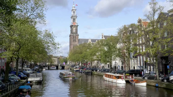 AMSTERDAM, PAÍSES BAJOS 12 DE OCTUBRE DE 2017: un barco de turismo en un canal con westerkerk en la distancia en Amsterdam — Foto de Stock
