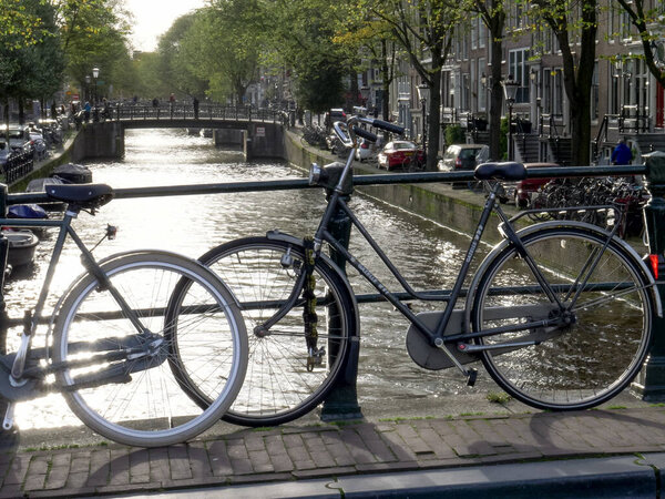 bicycles silhouetted on a bridge over a canal in amsterdam