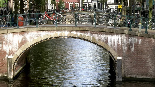 Bicicletas encadenadas a un puente sobre un canal en Amsterdam — Foto de Stock