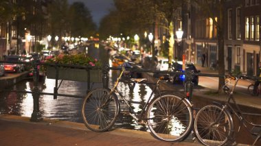 Hollanda 'da Amsterdam' da bir kanalın üzerinde bir bisikletin gece görüntüsü.