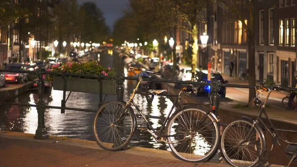 Toma nocturna de una bicicleta en un puente sobre un canal en Amsterdam en los Países Bajos — Foto de Stock