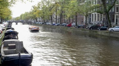 Öğleden sonra güneşli bir kanal manzarası ve Amsterdam 'da bir tur teknesi.