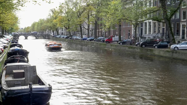 Eftermiddag utsikt över en solbelyst kanal och en turbåt i Amsterdam — Stockfoto