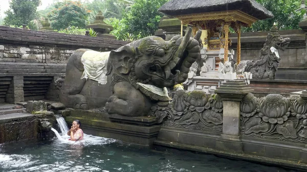 MANUKAYA, INDONESIEN - 22. MÄRZ 2018: Frau badet am Brunnen der heiligen Quelle unter einer Elefantenstatue in Bali — Stockfoto