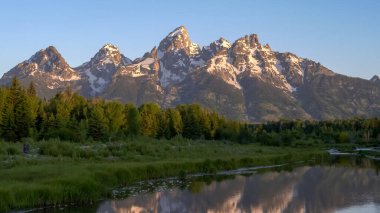 Grand Teton 'un gündoğumu ve Schwabacher adasında bir akarsu.