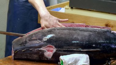 Tokyo 'daki Tsukiji balık pazarında bir ton balığını kesen bir işçiye yakın çekim.