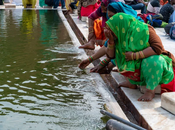 Egy nő zöld száriban megmossa az arcát a delhi-i jama masjid mecset előtt. — Stock Fotó