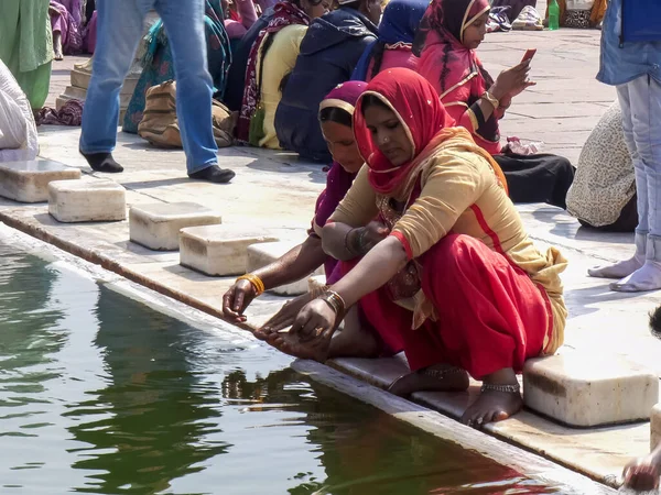 DELHI, INDIA - 11 marca 2019: kobieta w czerwonym sari myje ręce w meczecie Jama Masjid w Delhi — Zdjęcie stockowe