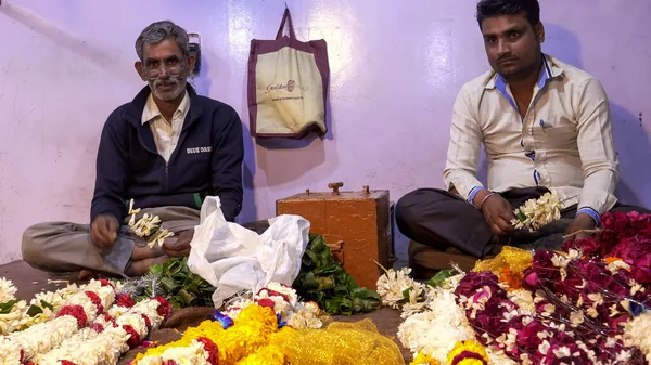 DELHI, ÍNDIA - MARÇO 12, 2019: dois trabalhadores do sexo masculino fazem guirlandas de flores no velho delhi na Índia — Fotografia de Stock