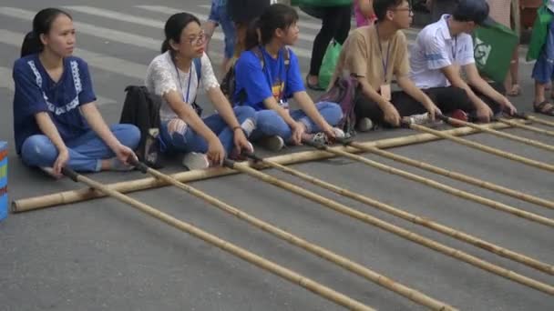 Close-up de vários jovens vietnamitas movendo postes de bambu para um jogo de tinikling perto de lago kiem hoan em hanoi — Vídeo de Stock